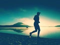 Silhouette of sport active man running on the lake beach at sunrise. Healthy lifestyle. Royalty Free Stock Photo