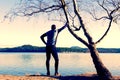 Silhouette of sport active man in running leggins and blue shirt at birch tree on beach. Calm water, island and sunny day Royalty Free Stock Photo