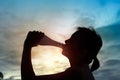 Silhouette of sport woman drinking water on sunset. Royalty Free Stock Photo