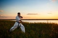 Silhouette of sportive man training karate in field at sunrise. Royalty Free Stock Photo