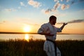 Silhouette of sportive man training karate in field at sunrise. Royalty Free Stock Photo