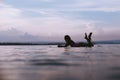 silhouette of sportswoman lying on surfing board in ocean