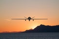 Silhouette of spy drone flying over sea UAV and on the background beautiful view of sun hiding behind surface of mountain