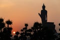 Silhouette of standing Buddha statue in Abhaya Mudra pose and left hand raising with sun rising from the opposite side