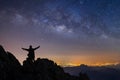 Silhouette of a standing man on top of a cliff with arms raised at night landscape mountain and milky way  galaxy Royalty Free Stock Photo