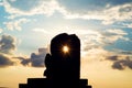 Silhouette statue with sun lens flare through the statue's hole in sunset