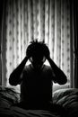 Silhouette of stressed man holding his head in the dark.