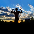 Silhouette of a strong muscular man on a background of sunset sky. Royalty Free Stock Photo