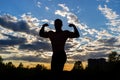 Silhouette of a strong muscular man on a background of sunset sky. Royalty Free Stock Photo