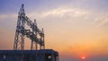 Silhouette structure of unconnected high-voltage electric pylons with power distribution building station in at sunset