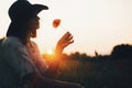 Silhouette of stylish girl in linen dress holding poppy flower in meadow in sun light with flowers in rustic straw basket. Boho Royalty Free Stock Photo