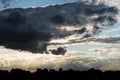 Silhouette of suburban scenery under dramatic backlit clouds.