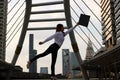 Silhouette of successful young Asian business woman raising her arms with document folder at urban building background. Royalty Free Stock Photo