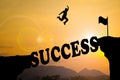 Silhouette sunset background. A man are jumping over to cliff and jump across success word. Royalty Free Stock Photo