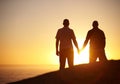 Silhouette, sunset and a gay couple at the beach holding hands for bonding, love and a date. Back, dark and lgbtq men Royalty Free Stock Photo