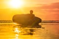 Silhouette of surf man sitting with a surfboard on the seashore beach at sunset time Royalty Free Stock Photo