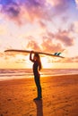 Silhouette with surfer girl holding surfboard on a beach at warm sunset or sunrise. Surfer and ocean Royalty Free Stock Photo