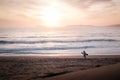 Silhouette of a surfer walking in the beach during sunset Royalty Free Stock Photo