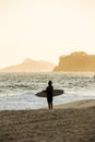 Silhouette of surfer walking on the beach during sunset