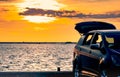 Silhouette SUV car with sport and modern design parked on concrete road by the sea at sunset. Road trip travel on vacation Royalty Free Stock Photo