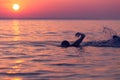 Swimmer at sunset over sea