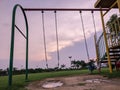 Silhouette of swing set at dusk with puddles of water during monsoon