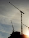 Silhouette of tall construction cranes at sunset. Dark moody sky. Construction industry. Building new commercial office of