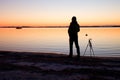 Silhouette of tall nature photographer at tripod taking picture on beach at sunset Royalty Free Stock Photo