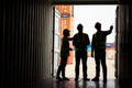 Silhouette of Team engineer dock control logistics worker wear safety helmets and protect suite open cargo container door and Royalty Free Stock Photo