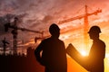 Silhouette Teams engineer looking construction worker in a building site at sunset