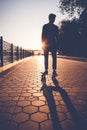 Silhouette of a teenage boy standing on a skateboard against the Royalty Free Stock Photo