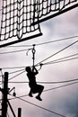 Silhouette of a teenage boy ziplining on zip line.