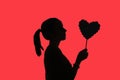 Silhouette of teenage girl with ponytail, holding flower heart i