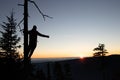 Silhouette of teenager dressed in winter clothes standing on branch and enjoying his feeling of victory from uprising of the Royalty Free Stock Photo