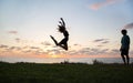 silhouette of teenager girl joyfully bounces, has fun at sunset by sea