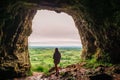 Silhouette of a teenager girl standing by a cave entrance, beautiful nature in the background. Travel, holiday and adventure Royalty Free Stock Photo