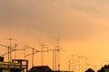 Silhouette, telecommunication towers with TV antennas and satellite dish in sunset. Many home TV antennas and satellite mounted