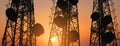 Silhouette, telecommunication towers with TV antennas and satellite dish in sunset, panorama composition Royalty Free Stock Photo