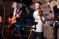 Silhouette of Television Camera hanging on crane working on stage and blurry concert background