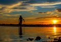 Silhouette of Thai Fisherman catching the fish in twilight Beautiful Sunset in the sky with sky blue and orange light of the sun