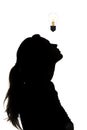 Silhouette of thoughtful woman looking at the incandescent lamp upwards, thought bulb, concept of idea on white isolated backgroun Royalty Free Stock Photo