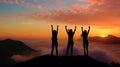 Silhouette of three girls with arms raised on top of a mountain above the clouds at sunset or sunrise. Royalty Free Stock Photo