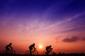 Silhouette three men ride bikes at sunset with orange-blue sky background