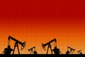 Silhouette of three oil pumps at orange background.