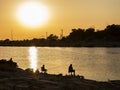 silhouette of three people fishing in the river at sunset, tranquil scene Royalty Free Stock Photo