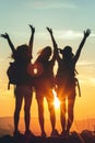 Silhouette of three people with raised hands on a mountain at sunset with high peaks behind Royalty Free Stock Photo