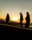 silhouette of three people walking with sunrise background