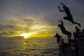 Silhouette of three young man jumping during awesome sunset