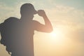 Silhouette of a tourist backpacking a man wearing a cap is going out to the world