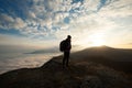 Silhouette of tourist hiker with backpack standing on the top of the mountain and looking at beautiful yellow autumn Royalty Free Stock Photo